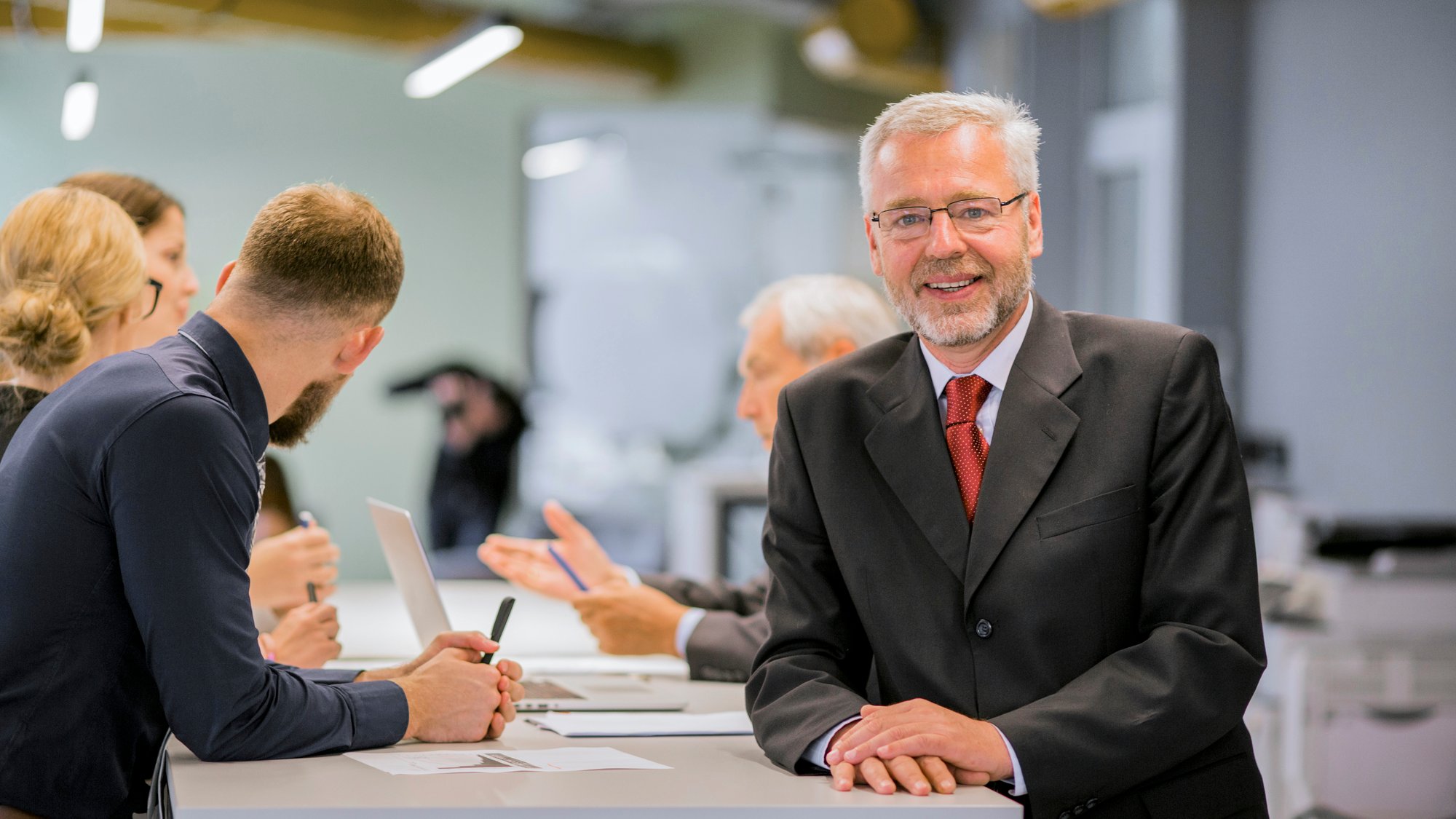 portrait-senior-businessman-front-businesspeople-discussing-office (1)